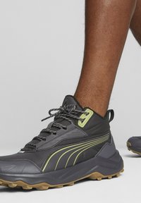 Scarpe da ginnastica nere con upper in rete, dettagli verde lime, suola testurizzata e punta rinforzata. Presentano lacci grigi e una linguetta sul tallone.