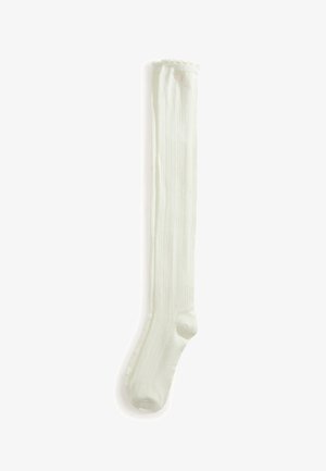 Longue chaussette blanche côtelée montant au genou avec une petite bordure en dentelle décorative en haut, présentée à plat sur fond blanc.
