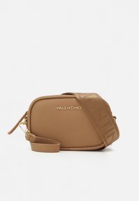 Hnědá kožená kabelka Valentino přes rameno se zlatým logem a širokým koženým páskem se stejným vzorem, na kterém je vyraženo jméno značky.