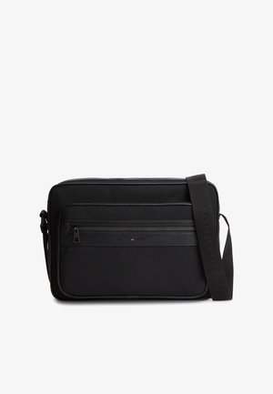 Black rectangular crossbody bag with front zip pocket and adjustable strap embossed with brand name.