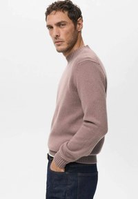 Jasnofioletowy sweter z dzianiny o okrągłym dekolcie, z ściągaczami na mankietach i u dołu, noszony na ciemnoniebieskich dżinsach. Miękka faktura, dopasowany krój.