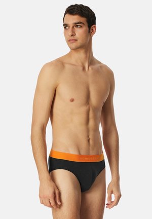 Slip neri con fascia elastica arancione, con il nome del marchio "SCHIESSER" in un colore a contrasto. Tessuto liscio, design aderente.