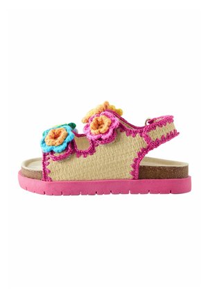 Child's open-toe sandal with pink sole, beige woven upper, pink trim, and multicolored crocheted flower decorations on straps.