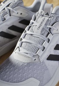 Szare buty sportowe z siateczkową cholewką, białymi sznurowadłami i czarnymi paskami. Posiadają wyściełany język i uchwyt na kołnierzu.