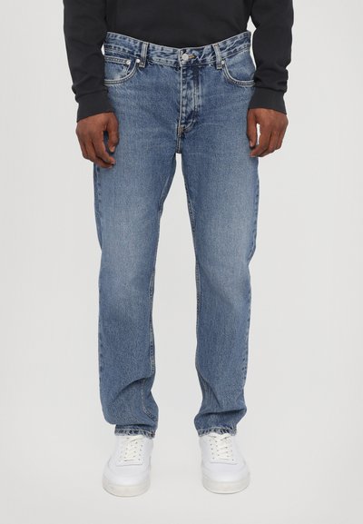 Lyseblå denimjeans med normal pasform, der har fem lommer, knaplukning og subtil falming. Kombinationen med hvide sneakers.