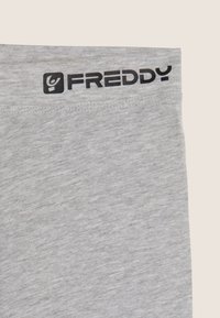 Leggings grigie con una texture morbida, caratterizzate da un logo nero "FREDDY" sulla cintura. Il tessuto sembra leggero e facile da indossare.