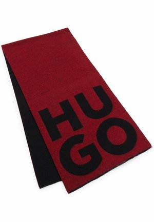 Écharpe bicolore pliée, rouge et noire, avec de grandes lettres noires formant "HUGO" sur la partie rouge.