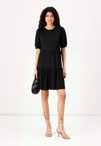 Vestido preto de mangas curtas com corpete ajustado, cintura franzida e saia rodada. O tecido é suave; apresenta um decote redondo e mangas bufantes.