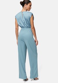Himmelblauer Jumpsuit mit kurzen Ärmeln, gerafftem Taillenbereich und weitem Bein-Design. Verfügt über einen Schlüsselaugenöffnung hinten und glattes, glänzendes Material.
