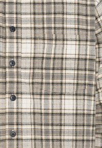 Ruudullinen paita mustalla, harmaalla ja beigen värillä. Sisältää napituskohdan ja pehmeän tekstuurin. Kuosi koostuu ristikkäisistä viivoista ja neliöistä.