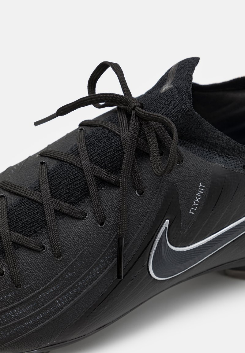 Zapatilla deportiva negra con parte superior de Flyknit, superficie texturizada, cordones negros planos y un swoosh blanco de Nike en el lateral.