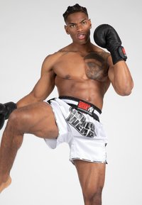 Bokser in zwarte handschoenen en witte shorts met het "GORILLA WEAR" logo. De shorts hebben een zwarte tailleband en een gladde textuur.