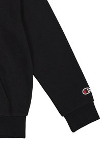 Manche de sweat-shirt noire en tissu mélange de coton, avec un poignet côtelé et un petit logo brodé en rouge et blanc.
