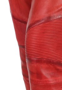 Rode leren broek met ribbeltextuur op de knieën en gladde gedeelten op de bovenbenen, met een strakke pasvorm en glanzende afwerking.