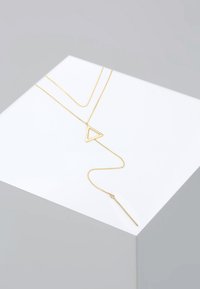 Collier en plaqué or avec un pendentif triangulaire et un pendentif en barre fine et allongée. Les chaînes sont délicates avec une texture lisse.