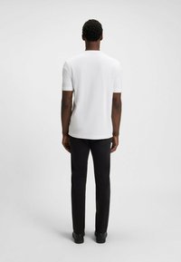 Heren T-shirt met korte mouwen, wit, met een ronde hals, gecombineerd met zwarte broek. Zachte stof, slim fit en naadloze achterkant.