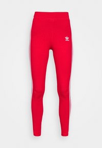 Röda leggings gjorda av stretchigt tyg, med vita sidostråk och en liten vit Adidas-logotyp på övre vänstra sidan.