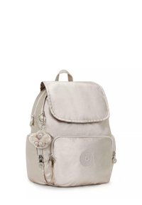 Sac à dos beige à finition satinée avec une fermeture à rabat, une poche zippée à l'avant et un porte-clés en forme de singe. Présente un emblème de logo rond.