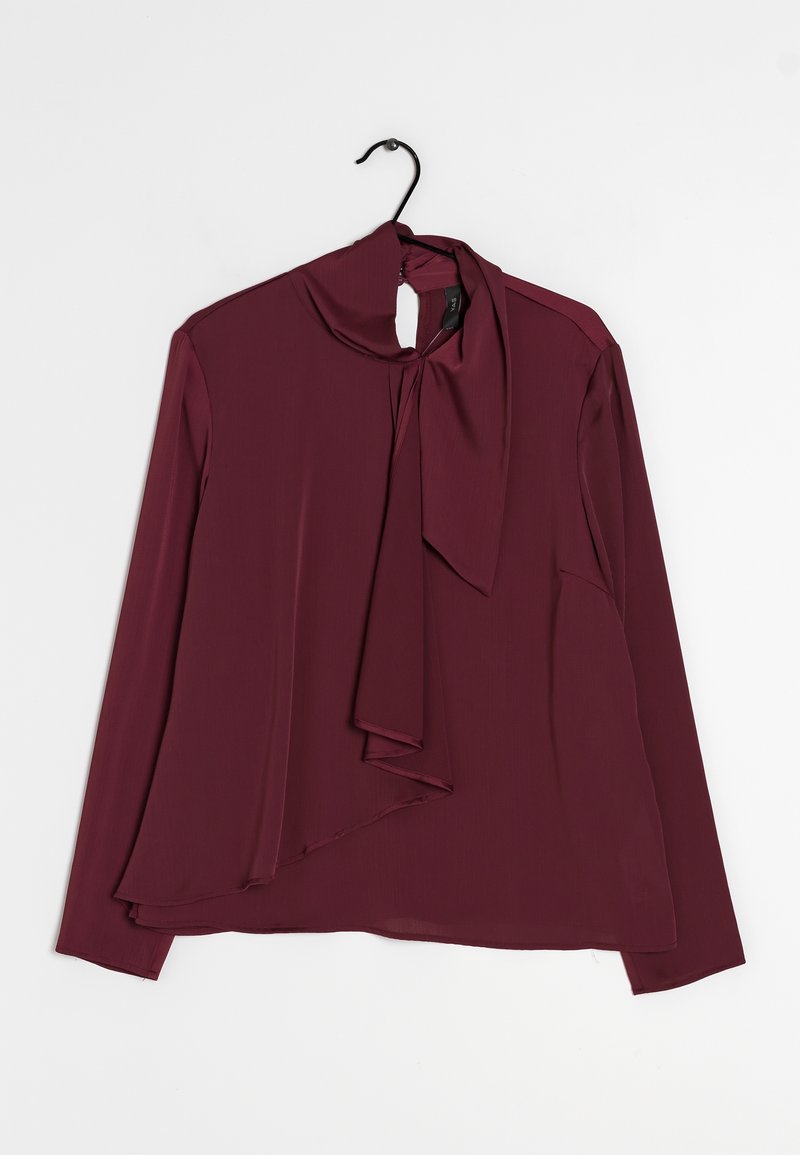 Blusa bordeaux con maniche lunghe, davanti drappeggiato e dettaglio a fiocco sul collo. Tessuto liscio e leggero con orlo asimmetrico.