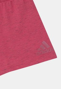 Rosaidrottsshorts i mjukt material, med en subtil heather-textur och en grå Adidas-logga på nedre vänster sida.