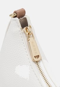 Vit texturerad läderväska med ett gulddragkedja och en rektangulär dragflik präglad med "VALENTINO" samt en brun läderdetalj på toppen.