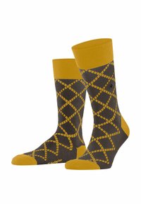Żółto-szare skarpetki z geometrycznym wzorem w diamenty. Gładka powierzchnia z materiałem ściągającym w kolorze żółtym. Wzmocnione palce i pięty.