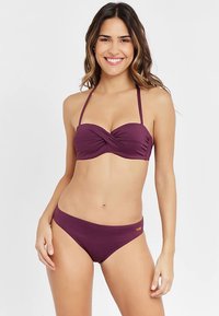Violetinis bikinis su sukrištais bandeau viršumi ir derančiomis žemuoju liemeniu. Pagamintas iš lygaus audinio su reguliuojamomis petnešėlėmis ir minimalistiniu dizainu.
