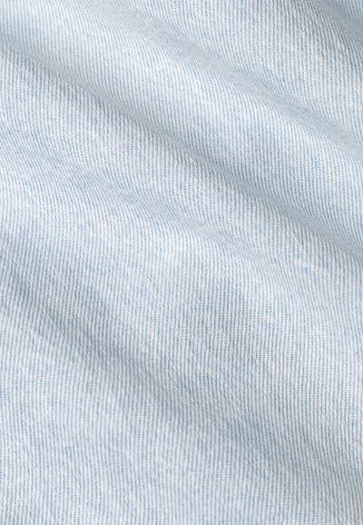 Un tissu en denim bleu clair avec une texture lisse, présentant un subtil motif de tissage diagonal et de fins détails de couture.