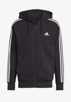 Felpa nera con zip realizzata in tessuto morbido, con dettagli a tre strisce bianche sulle maniche e cappuccio regolabile con cordino. Logo Adidas sul petto.