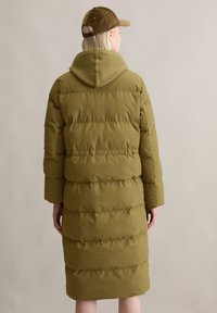 Olijfgroen gewatteerde jas met een geribde capuchon, gekenmerkt door een lange silhouet, horizontale quiltpatronen en zijzakken.