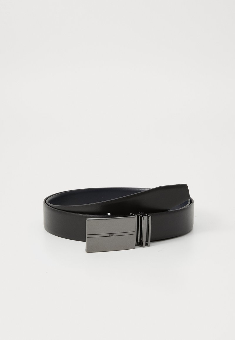 Ceinture en cuir noir enroulée avec une boucle métallique rectangulaire présentant deux lignes horizontales et un petit logo centré.
