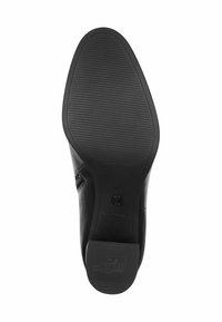 Suela de zapato negra con agarre texturizado, pequeño tacón etiquetado como "ANTI DESLIZAMIENTO" y costura visible a lo largo del borde.