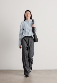 Blå og hvidstribet langærmet skjorte, grå vidde bukser, sort taske og sko. Simpelt design med afslappet pasform og casual stil.