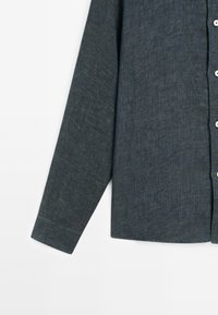 Dark blue long-sleeve shirt made of textured fabric with a button-down front, featuring white buttons and a cuffed sleeve design.