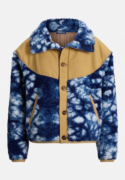 Chaqueta de forro polar con un patrón tie-dye azul y blanco, parte superior en color marrón claro, botones delanteros y bolsillos laterales. Material texturizado que proporciona calor.