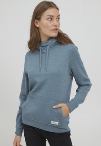 Ljusblå hoodie med känguruficka, dragsko i halsen och ribbade ärmslut. Mjuk tyg med en slät yta. Märkesetikett synlig.