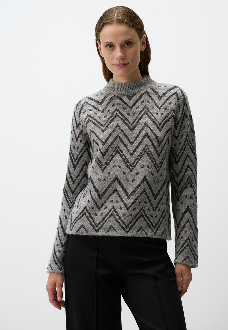 Grauer Pullover mit Chevron-Muster in Schwarz, hoher Ausschnitt und langen Ärmeln, aus strukturiertem Strickstoff gefertigt.
