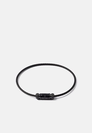 Bracelet en câble noir torsadé avec fermoir cylindrique gravé du nom de la marque, présenté sur fond blanc.
