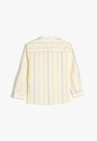 Langarmshirt in lichtcrème met gele en zwarte verticale strepen. Heeft een klassieke kraag en knoopmanchetten. Gewoven stof textuur.