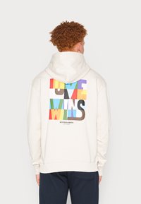 Felpa cremosa con grande grafica multicolore "LOVE WINS" sul retro. Polsini e orlo a coste, tessuto morbido, cappuccio spazioso e vestibilità casual.