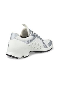 Υποδήματα με επάνω μέρος από άσπρο και ασημένιο πλέγμα, υφή από καουτσούκ στη σόλα και μοναδικό κυματιστό σχέδιο στις πλευρές. Διαθέτουν αντανακλαστικές λεπτομέρειες.