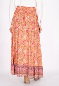 Lange, oranje bloemenrok met een elastische tailleband. Kenmerkt zich door roze en rode bloemen met een patroon aan de onderrand en een vloeiende silhouet.
