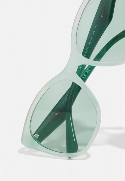 Light green sunglasses with oversized, angular frames and tinted lenses. The arms are also green, featuring subtle branding and a smooth finish.