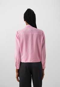 Short pink striped shirt with long sleeves, a collar, and buttoned cuffs, made of lightweight fabric. Features a back yoke design.