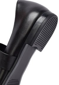 Scarpa nera in pelle con finitura liscia, tacco arrotondato, design minimalista e suola in gomma testurizzata per una migliore aderenza.