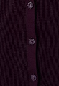 Tissu tricoté violet foncé avec patte de boutonnage verticale comprenant trois boutons noirs ronds cousus en colonne.