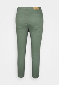 Calças ajustadas verde-oliva com uma textura suave, dois bolsos traseiros e um rótulo de couro castanho na cintura. Design simples de perna reta.