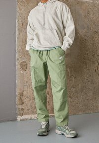 Ljusgrå hoodie med en ficka framtill, ihopparad med mintgröna cargo-byxor med sidofickor och en liten logotyp. Grå och gröna sneakers.