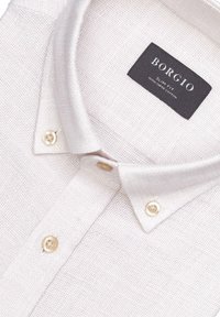 Jasny, fakturowany koszula z kołnierzykiem button-down. Metka głosi "Borgio, Slim Fit, 100% Bawełna Wyższej Jakości" na czarno.