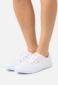 Hvite lerrets sneakers med rund tå, teksturert gummisåle og rosegull ögler; designet for casual bruk og med en klassisk snøring foran.
